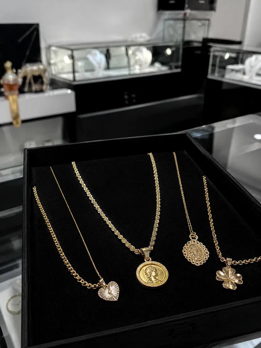 Bandeja de collares y dijes de oro en la vitrina de Joyería Kendra
